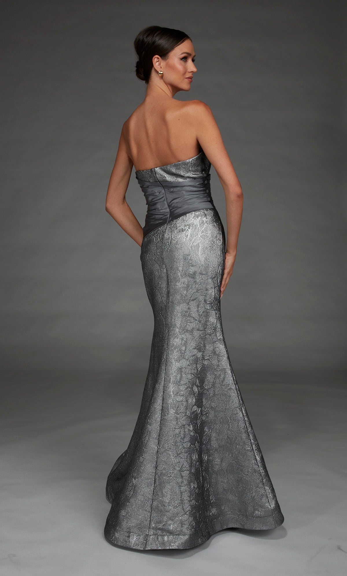 Woman wearing a silver strapless gown against a gray background