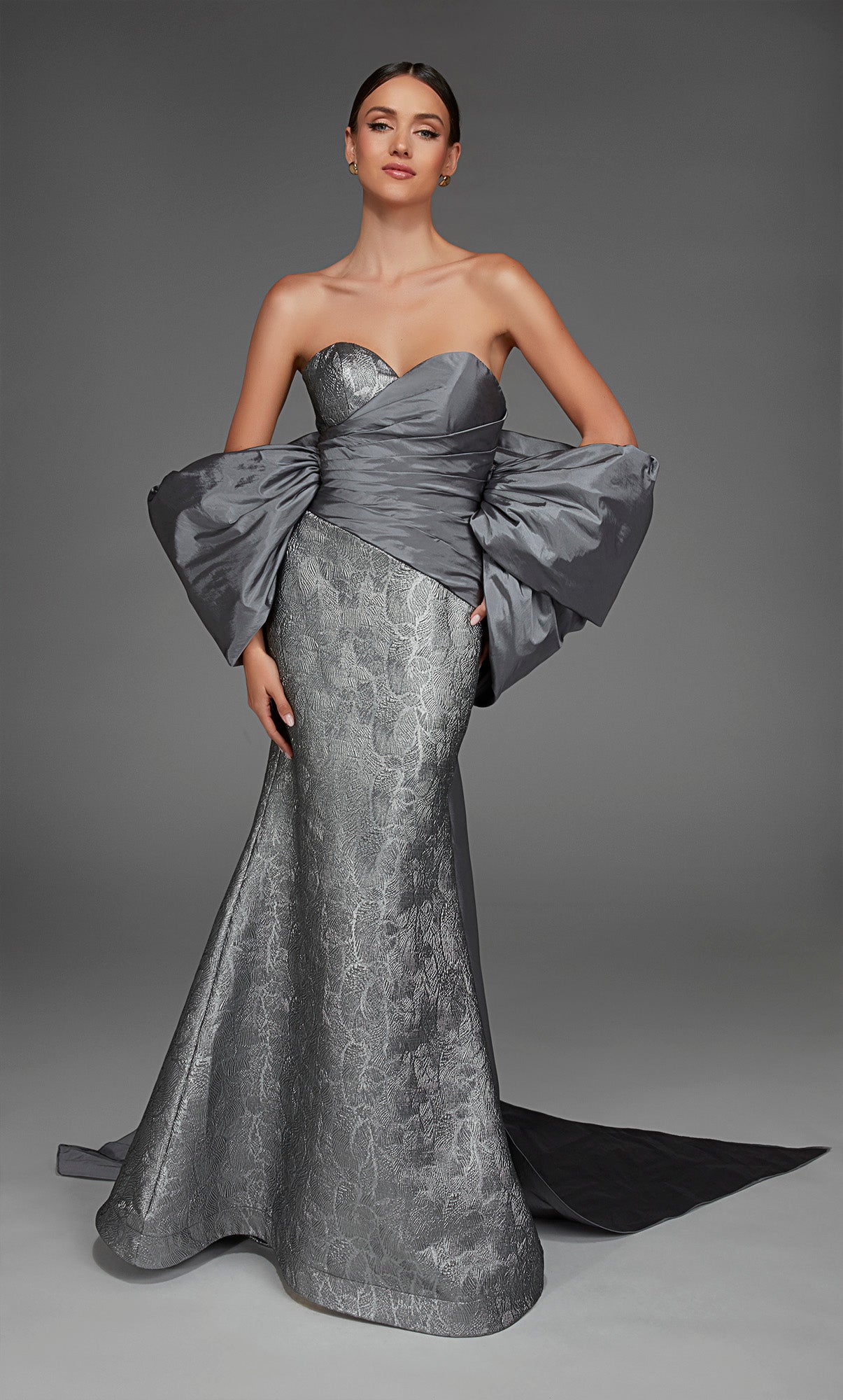 Woman wearing a silver strapless gown against a gray background